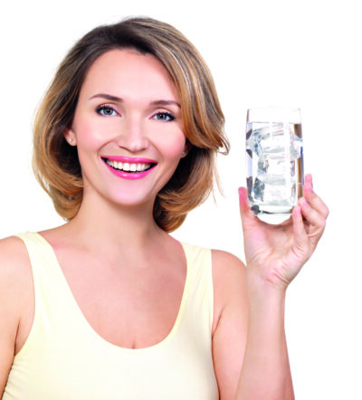 Beautiful young smiling woman with a glass of water on a white background